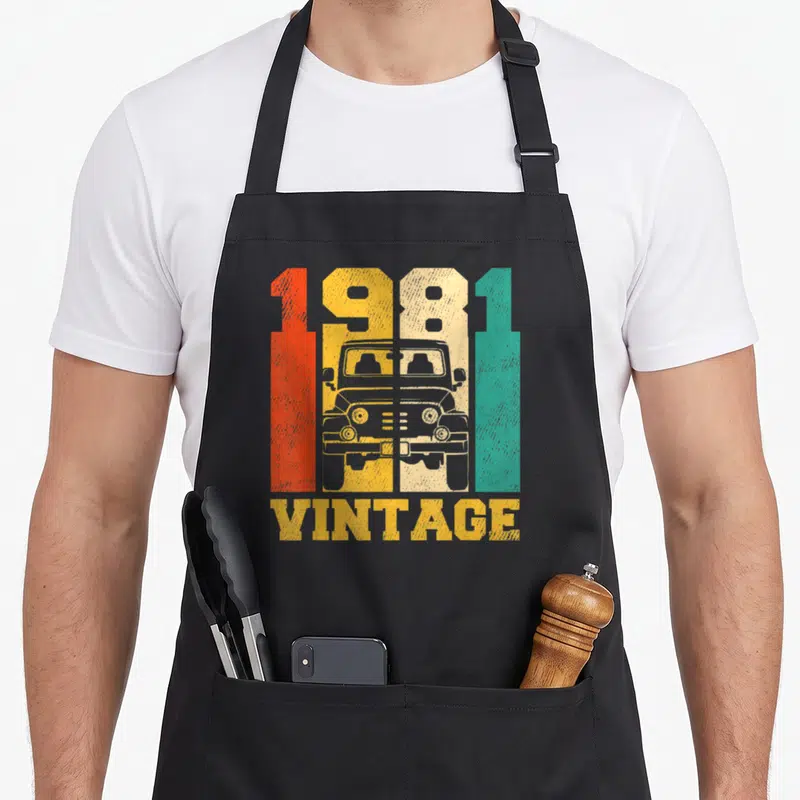 Tablier de cuisine noir avec illustration vintage 1981 4x4 et texte VINTAGE en lettres délavées orange jaune et vert.