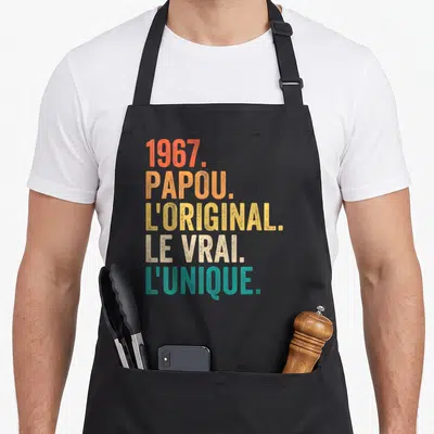 Tablier de cuisine noir avec typographie vintage multicolore mentionnant 1967 Papou L'original Le Vrai L'unique.