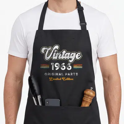 Tablier de cuisine noir avec le motif vintage 1966 Original Parts Limited Edition imprimé au centre.