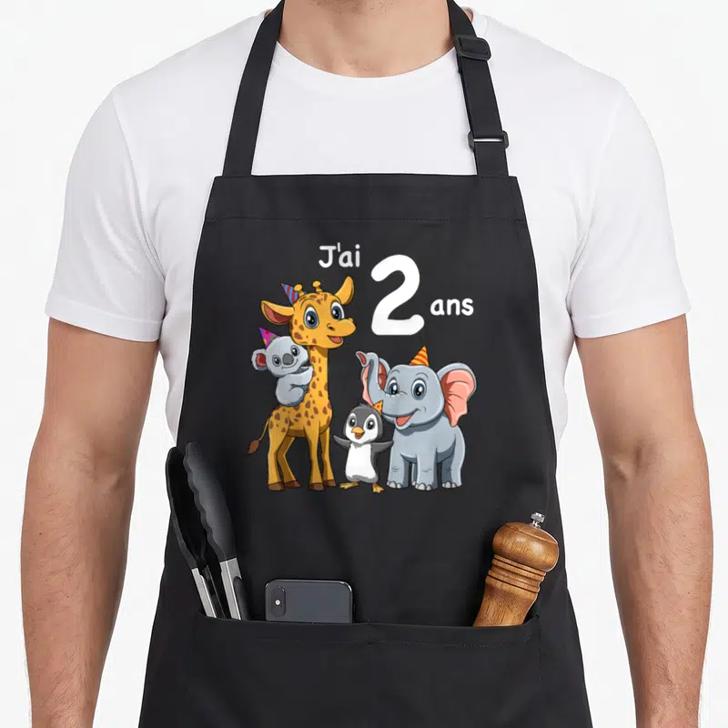 Tablier de cuisine noir avec girafe, éléphant, pingouin et koala portant des bonnets de fête colorés.