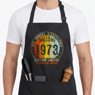 Tablier de cuisine noir avec logo circulaire rétro multicolore et texte des années d'excellence millésime 1973 édition limité exemplaire unique.