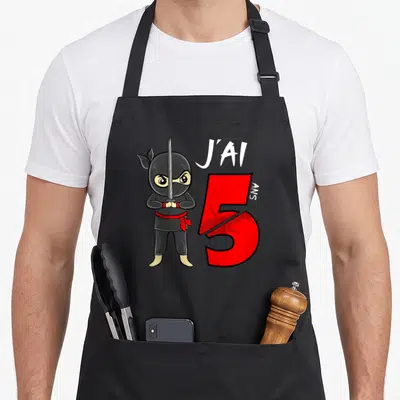 Tablier de cuisine noir avec ninja tenant un sabre et l'inscription J'ai 5 Ans en rouge et blanc.