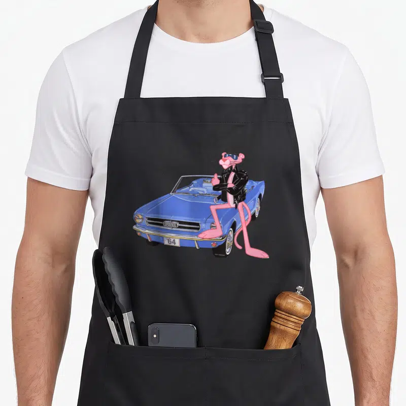 Tablier de cuisine noir avec le Pink Panther Cool Cat posant à côté d'une voiture cabriolet bleue vintage.