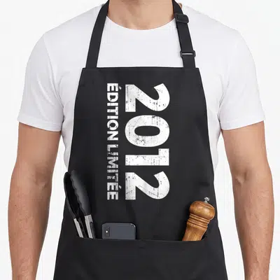 Tablier de cuisine noir avec inscription blanche 2012 « ÉDITION LIMITÉE » en typographie usée.