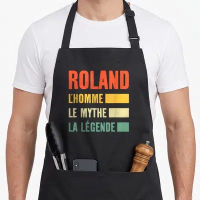 Tablier de cuisine noir avec inscription colorée Roland L'Homme Le Mythe La Légende et rectangles décoratifs.