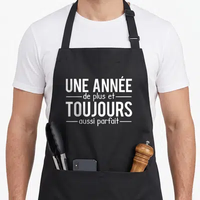 Tablier de cuisine noir avec inscription blanche Une Année De Plus Et Toujours Aussi Parfait centrée sur le devant.