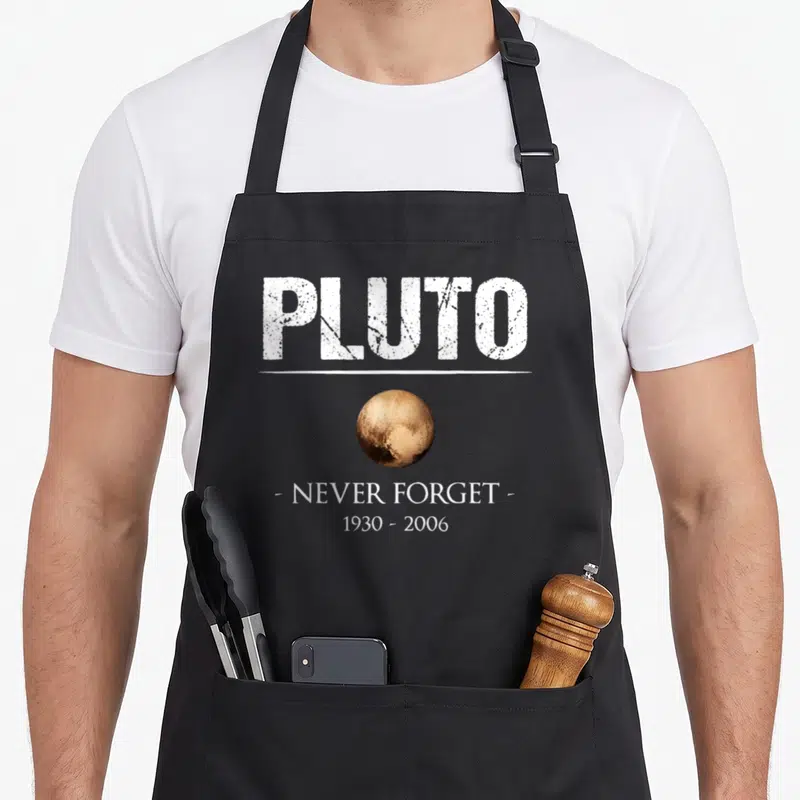Tablier de cuisine noir avec l'illustration de Pluton et le texte Pluto Never Forget 1930 2006 en blanc.