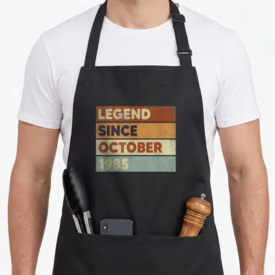 Tablier de cuisine noir avec motif rectangulaire aux bandes colorées et texte rétro.