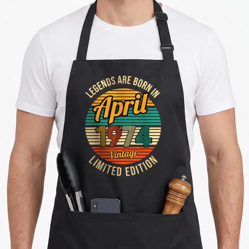Tablier de cuisine noir avec illustration circulaire retro et texte legends are born in april 1974 vintage limited edition