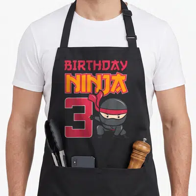 Tablier de cuisine noir avec illustration ninja et texte anniversaire Ninja 3 en couleurs vives.