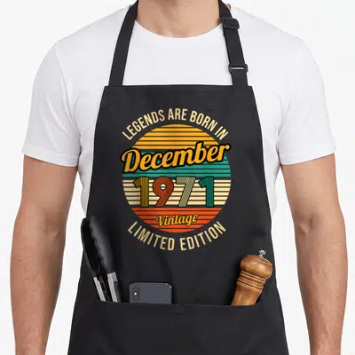 Tablier de cuisine noir avec un motif circulaire vintage coloré et du texte festif sur fond gris.