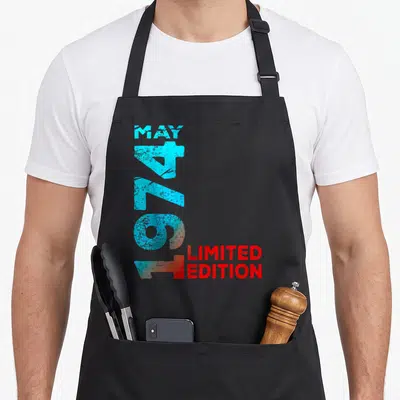 Tablier de cuisine noir avec typographie verticale turquoise 1974 et texte rouge Limited Edition sur le devant.