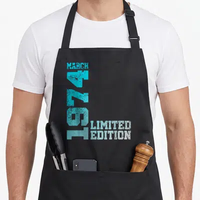 Tablier de cuisine noir avec typographie bleue indiquant mars 1974 limited edition en style vintage.