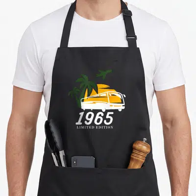 Tablier de cuisine noir avec autocar orange, palmiers verts et inscription 1965 Limited Edition en blanc.