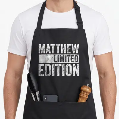 Tablier de cuisine noir avec inscription blanche texturée Matthew Limited Edition centrée sur la poitrine.