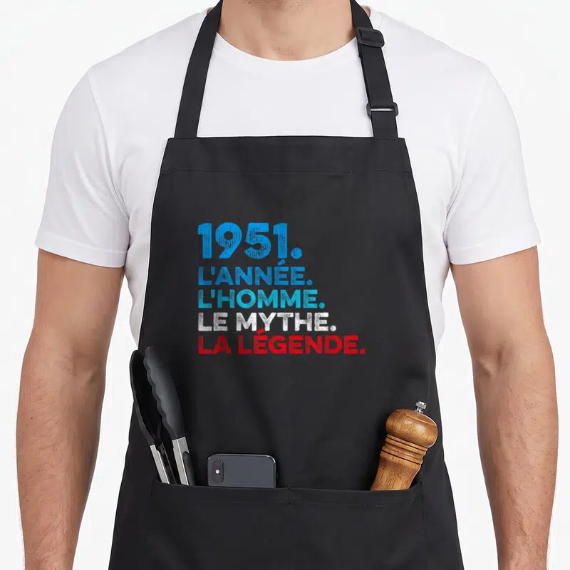 Tablier de cuisine noir avec inscription 1951 l'année l'homme le mythe la légende en bleu et rouge.