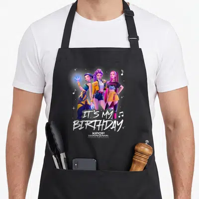 Tablier de cuisine noir avec trois personnages animés colorés et le texte It's My anniversaire en lettres blanches stylisées.