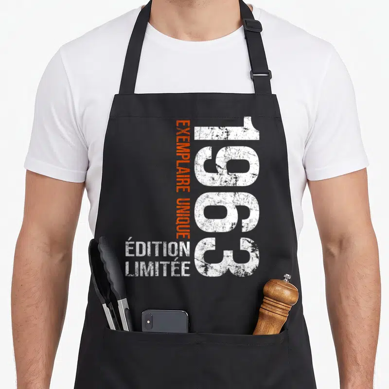 Tablier de cuisine noir avec l'année 1963 en blanc et texte exemplaire unique en orange vertical.