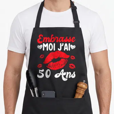 Tablier de cuisine noir avec inscription Embrasse Moi J'ai 50 Ans et traces de baisers rouges.