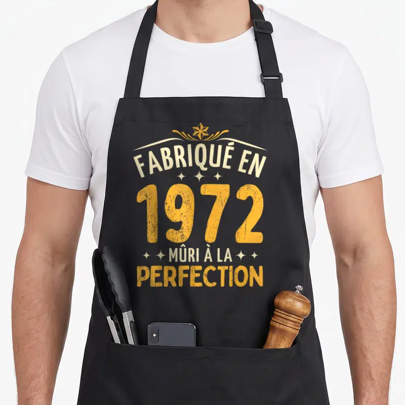 Tablier de cuisine noir avec l'inscription « fabriqué en 1972 » mûri à la perfection en typographie vintage orange et crème.