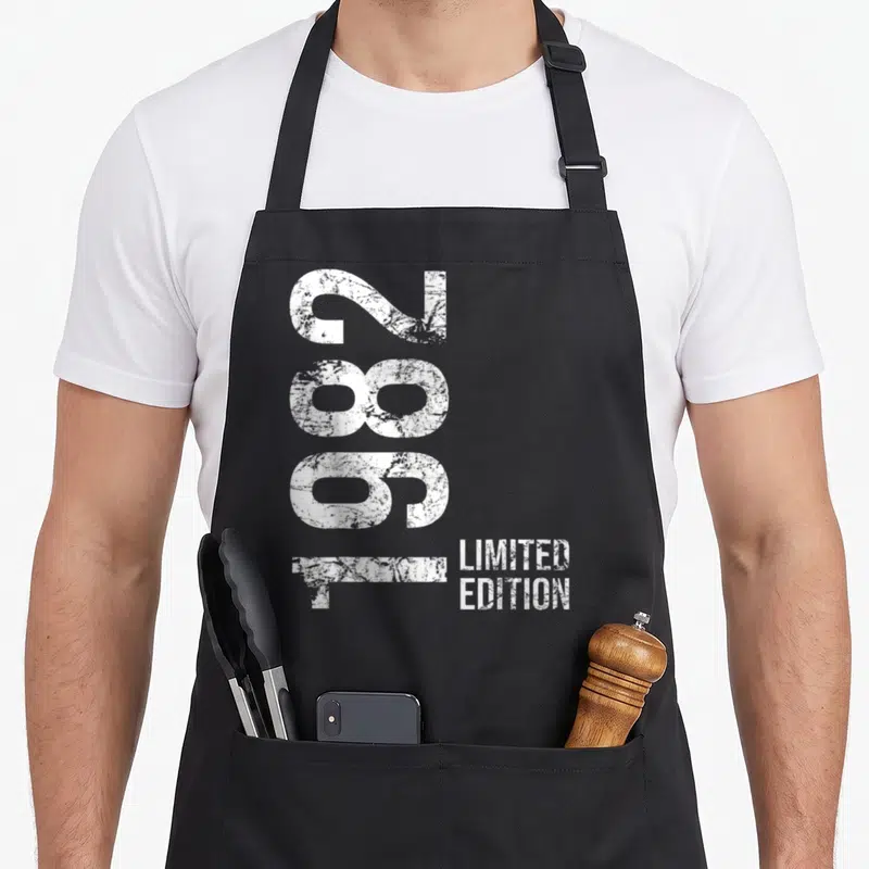 Tablier de cuisine noir avec l'année 2082 imprimée verticalement en blanc texturé et la mention limited edition en bas à droite.