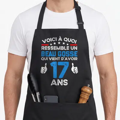 Tablier de cuisine noir avec inscription voici à quoi ressemble un beau gosse qui vient d'avoir 17 ans et deux mains faisant des pouces levés.