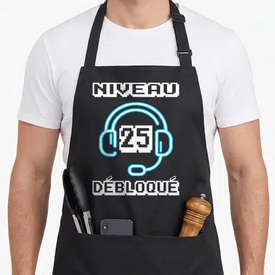 Tablier de cuisine noir avec casque gaming pixelisé bleu et texte Niveau 25 Débloqué en blanc.