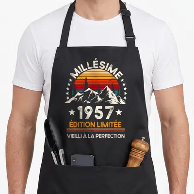 Tablier de cuisine noir avec illustration vintage de soleil couchant, montagnes et texte millésime 1957 « édition limitée » vieilli à la perfection.