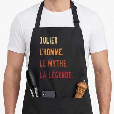Tablier de cuisine noir avec texte jaune orange et rouge disant Julien l'homme le mythe la légende