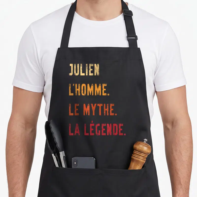 Tablier de cuisine noir avec texte jaune orange et rouge disant Julien l'homme le mythe la légende