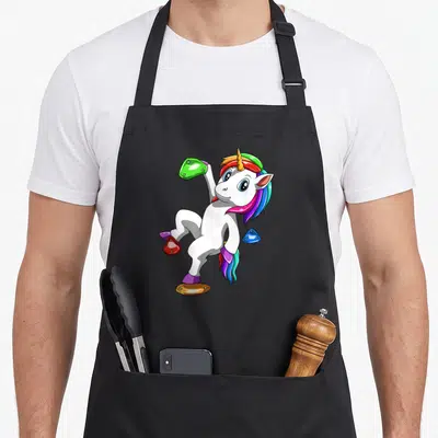 Tablier de cuisine noir avec une licorne blanche escaladant des prises colorées.