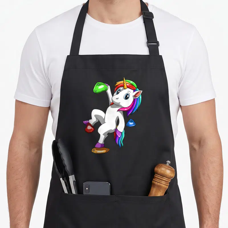Tablier de cuisine noir avec une licorne blanche escaladant des prises colorées.