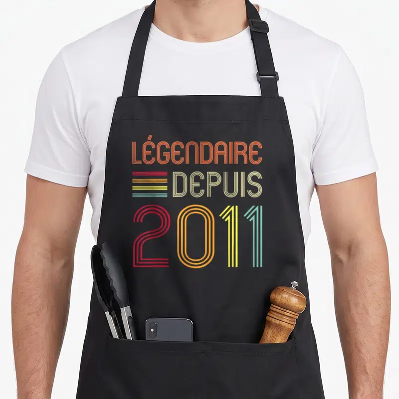 Tablier de cuisine noir avec inscription Légendaire Depuis 2011 en lettres multicolores style rétro.