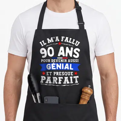 Tablier de cuisine noir avec texte blanc Il m'a fallu 90 ans pour devenir aussi génial et presque parfait sur fond uni.