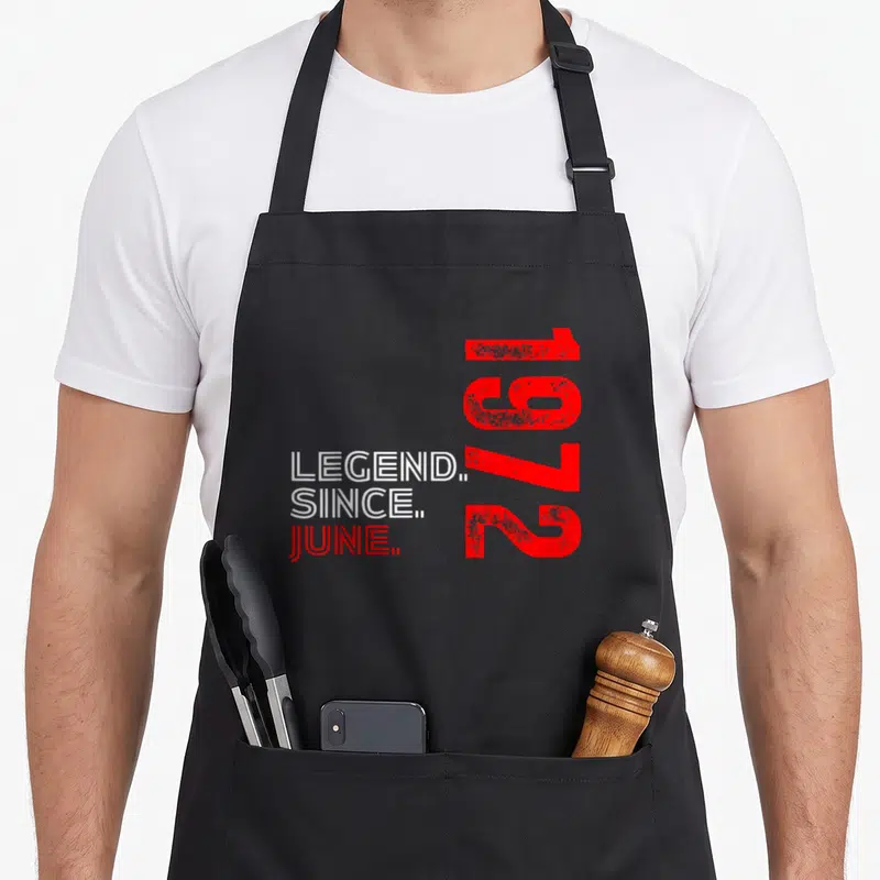 Tablier de cuisine noir avec inscription légende since juin 1972 en rouge et blanc sur fond gris uni.