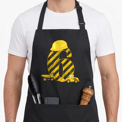 Tablier de cuisine noir avec grand chiffre 6 jaune, casque de chantier, bandes de sécurité et deux engins de construction imprimés.