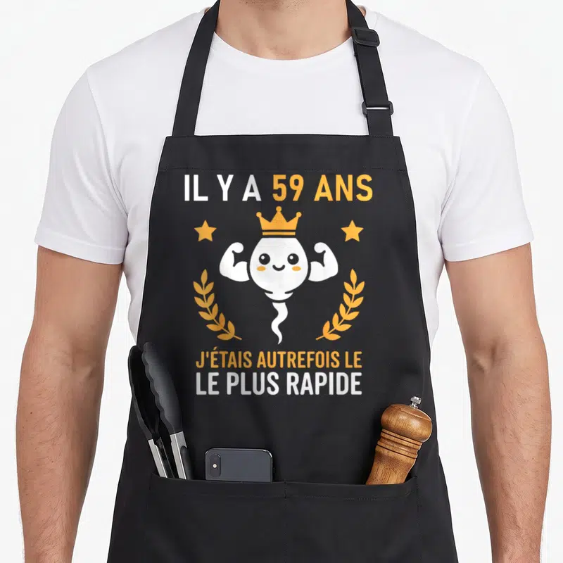 Tablier de cuisine noir avec illustration d'un spermatozoïde souriant couronné et texte sur 59 ans