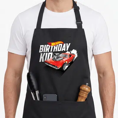 Tablier de cuisine noir avec une voiture rouge Hot Wheels et l'inscription anniversaire Kid en lettres blanches dynamiques.