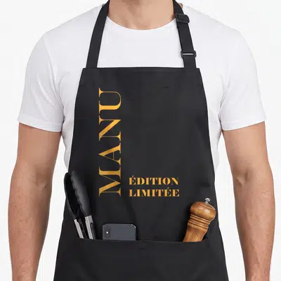 Tablier de cuisine noir avec le prénom Manu et « Édition Limitée » en lettres dorées verticales.