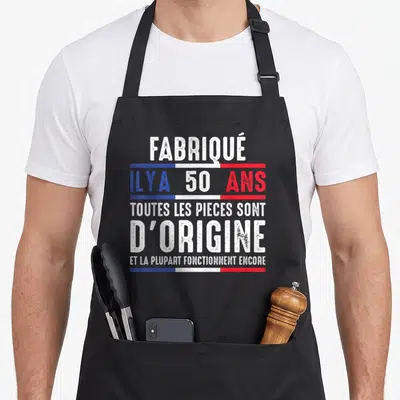 Tablier de cuisine noir avec inscription blanche et barres tricolores sur fond gris uni