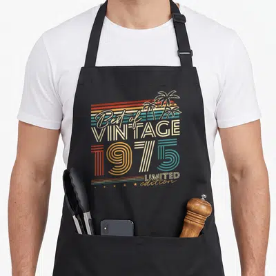 Tablier de cuisine noir avec illustration vintage Best of Vintage 1975 Limited Edition et palmiers stylisés.