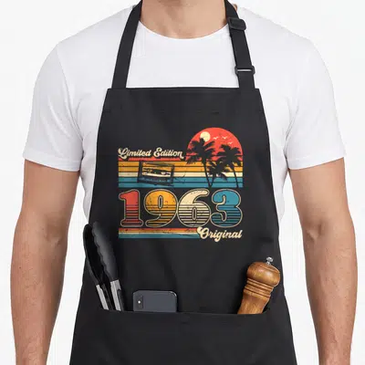 Tablier de cuisine noir avec motif vintage 1963 Limited Edition Original illustré d'une cassette et de palmiers.