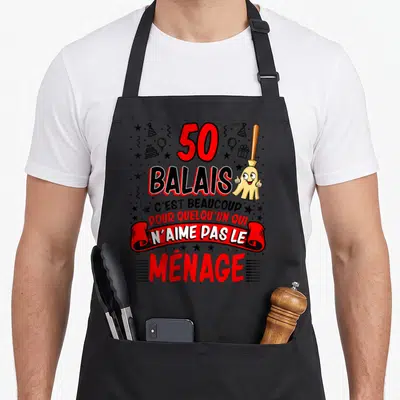 Tablier de cuisine noir avec un balai souriant et le texte 50 balais c'est beaucoup pour ménage en rouge et noir.