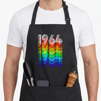 Tablier de cuisine noir avec 1964 en chiffres géométriques multicolores superposés verticalement.