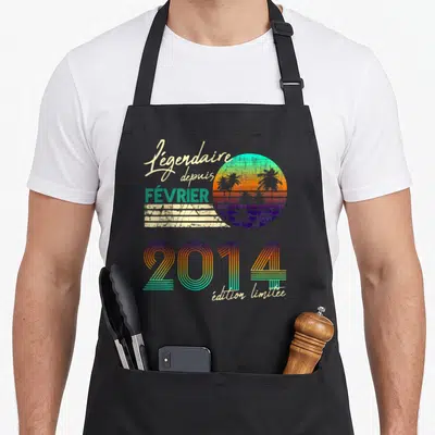 Tablier de cuisine noir avec motif rétro coloré affichant Légendaire depuis février 2014 « édition limitée » et un soleil aux palmiers.
