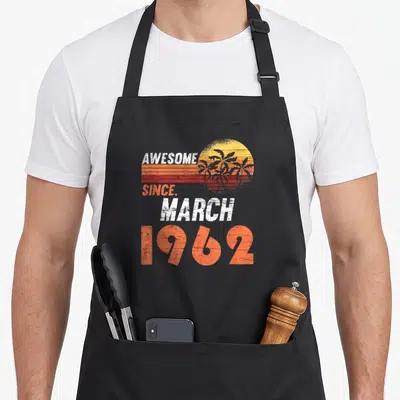 Tablier de cuisine noir avec inscription « Awesome Since March 1962 » et soleil rétro orange