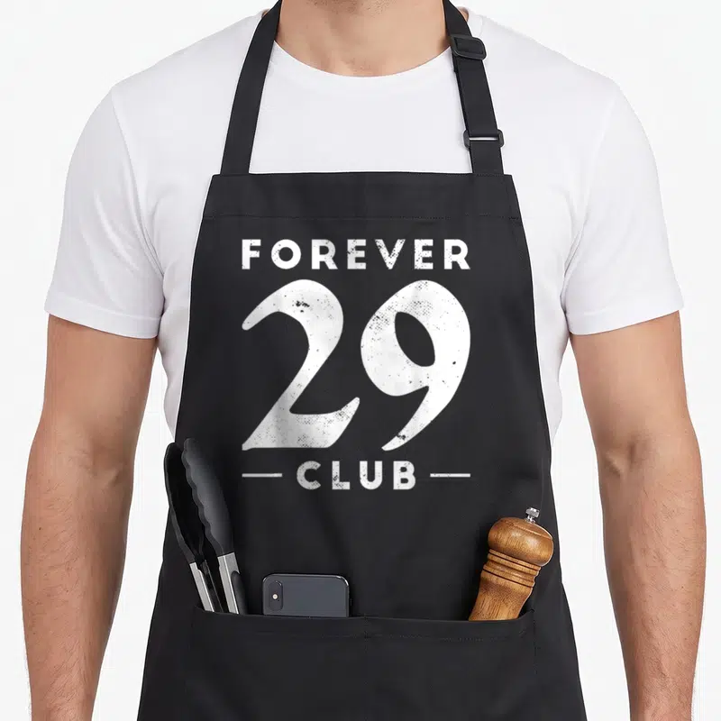 Tablier de cuisine noir avec inscription blanche Forever 29 Club au style vintage et texturé.