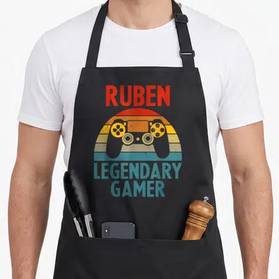 Tablier de cuisine noir avec illustration manette de jeu vidéo et texte Ruben legendary gamer en couleurs vintage.