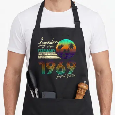 Tablier de cuisine noir avec motif rétro coloré affichant le texte Légendaire since February 1969 Limited Edition.
