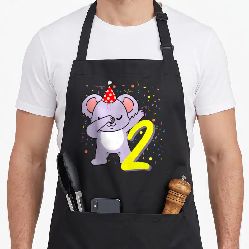 Tablier de cuisine noir avec un koala violet faisant le dab près d'un chiffre 2 jaune et de confettis.